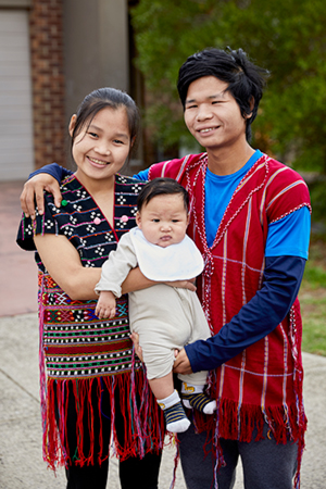 man and woman holding baby out front of their home